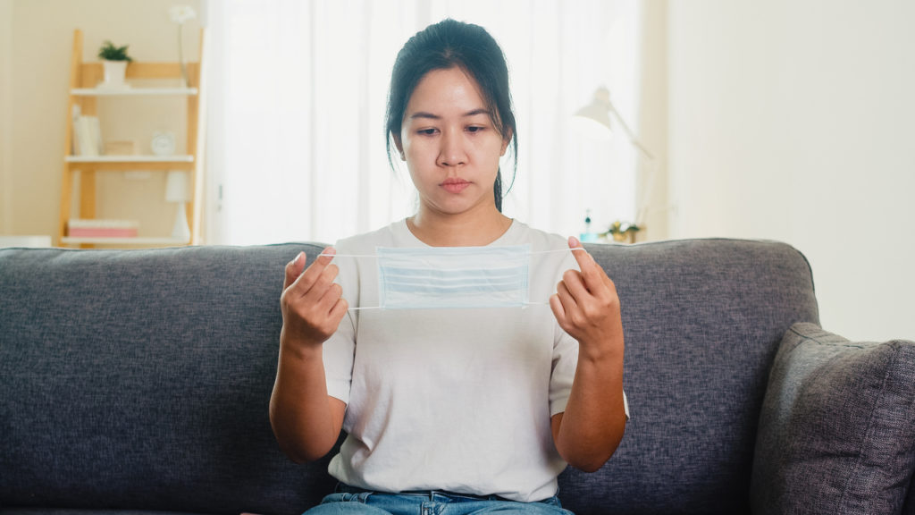 A depressed woman looking at a face mask